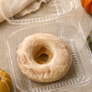 Round beige powdered donut in clear plastic tray on a light cloth surface