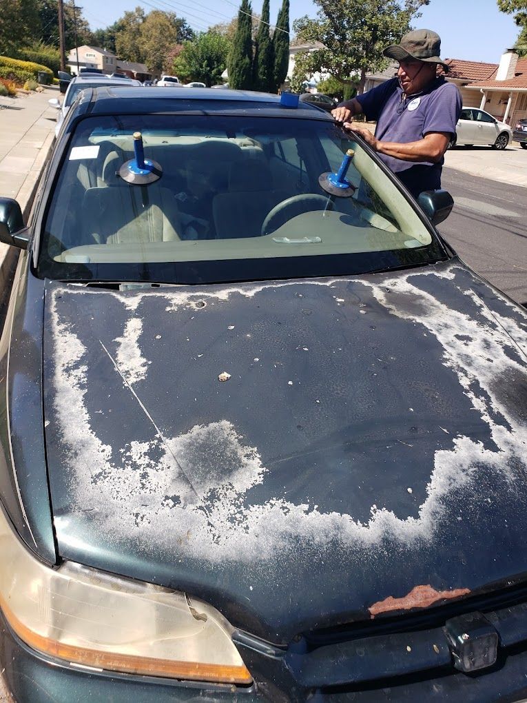 A man is fixing a windshield on a dirty car.