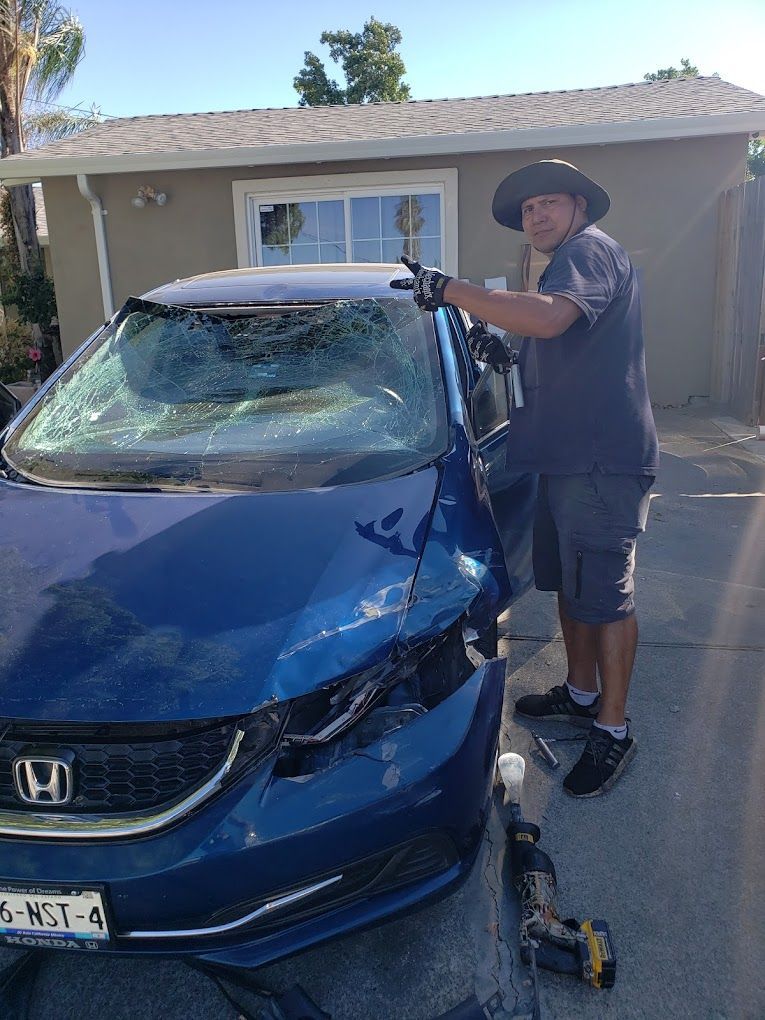 A man is working on a damaged honda civic