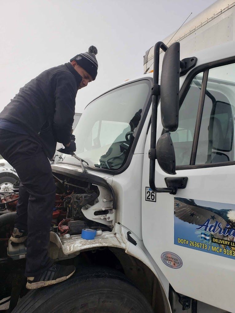 A man is working on the engine of a white truck