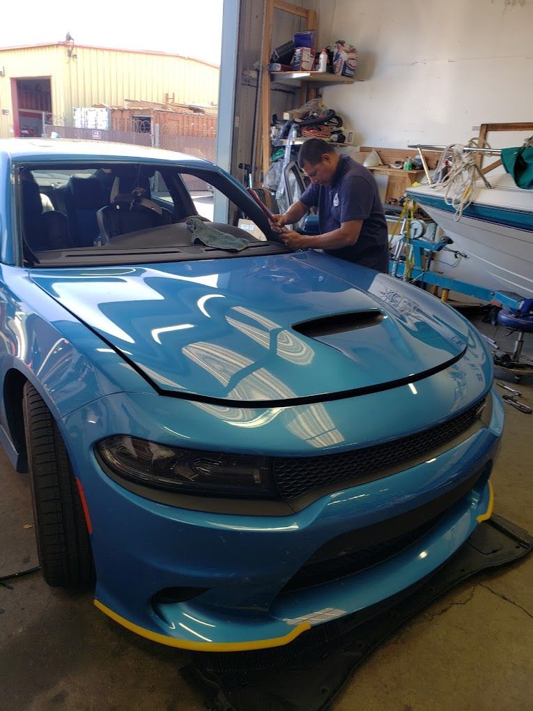 A man is working on a blue dodge charger in a garage.