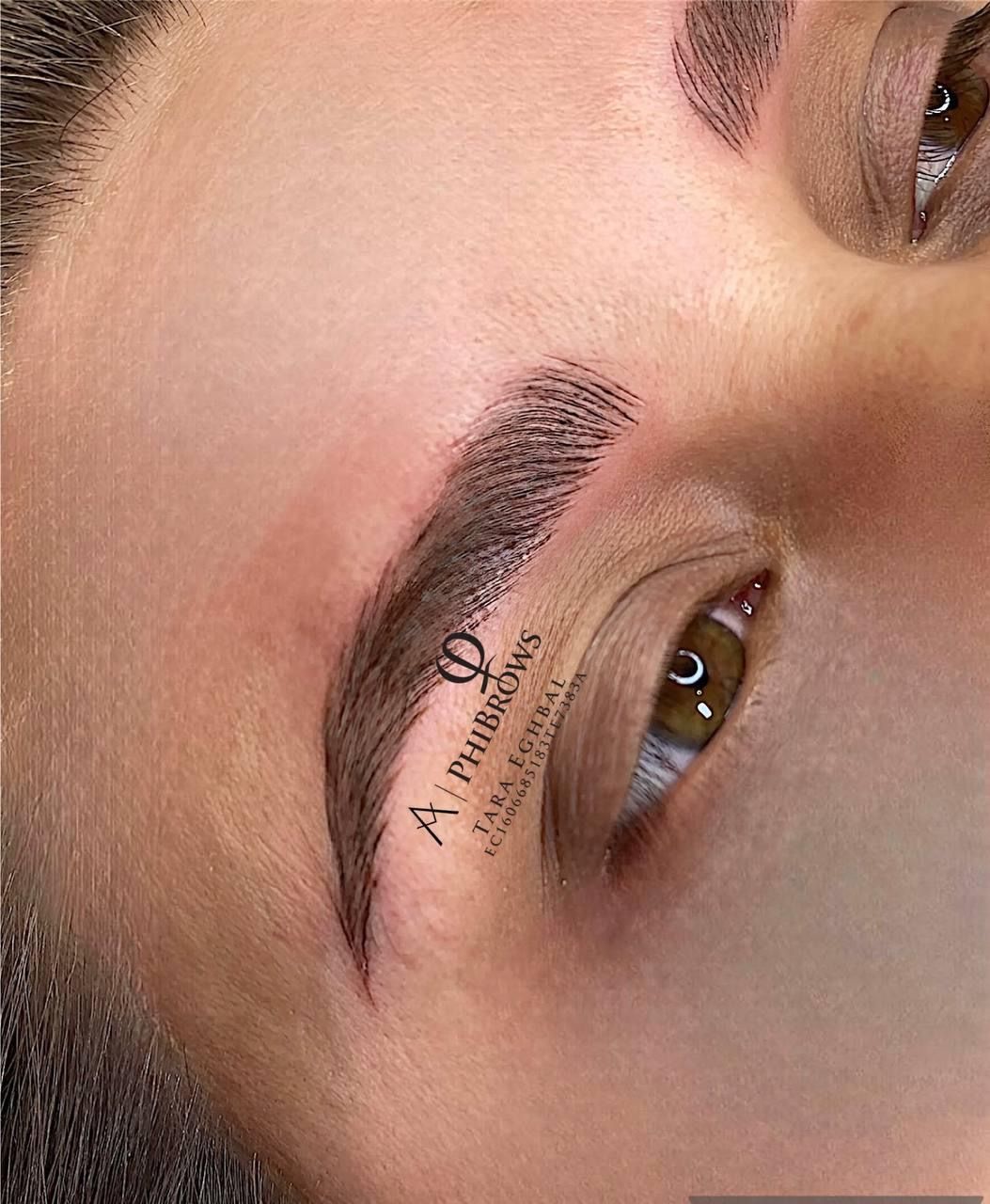 A close up of a person 's face with a tattoo on their eyebrow.