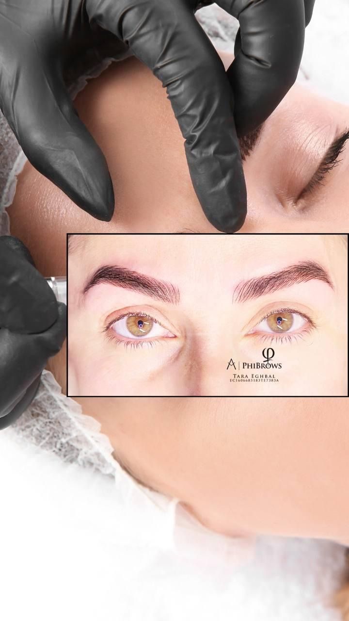 A woman is getting her eyebrows tattooed with a machine.