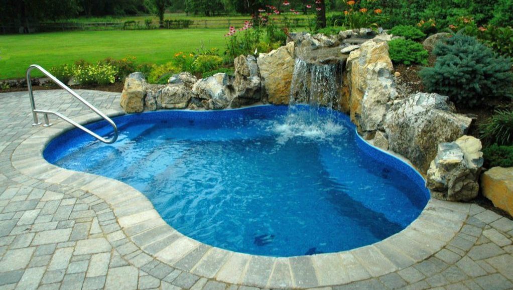 A small swimming pool with a waterfall in the backyard