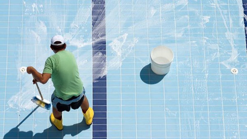 A man is cleaning a swimming pool with a broom.