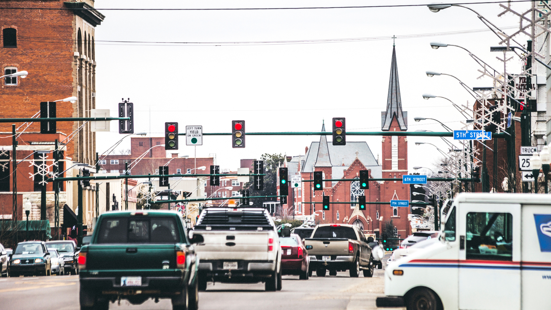 Street view with traffic, brick buildings, and a church steeple in fort smith, AR.
