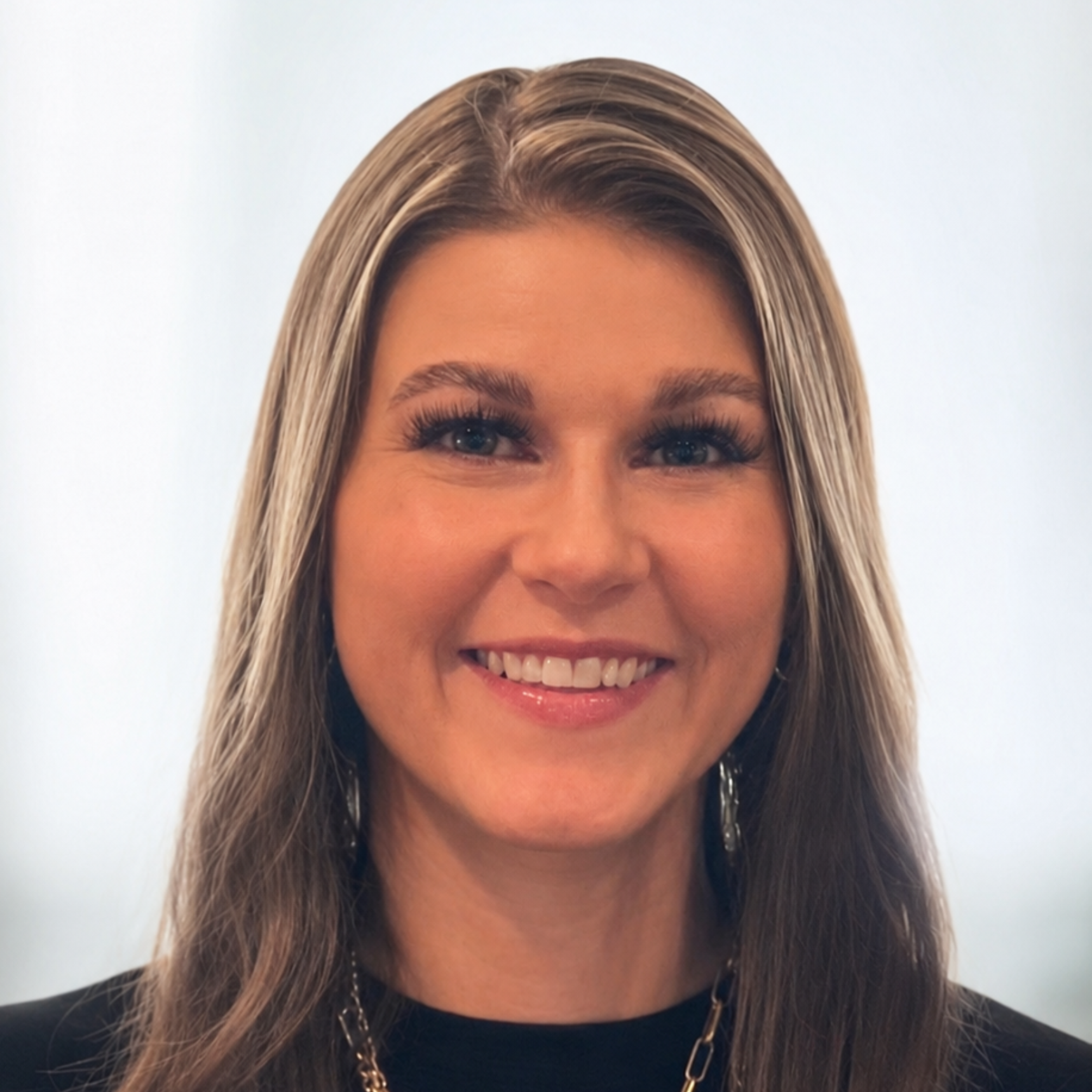 Smiling woman with long highlighted hair against a light background