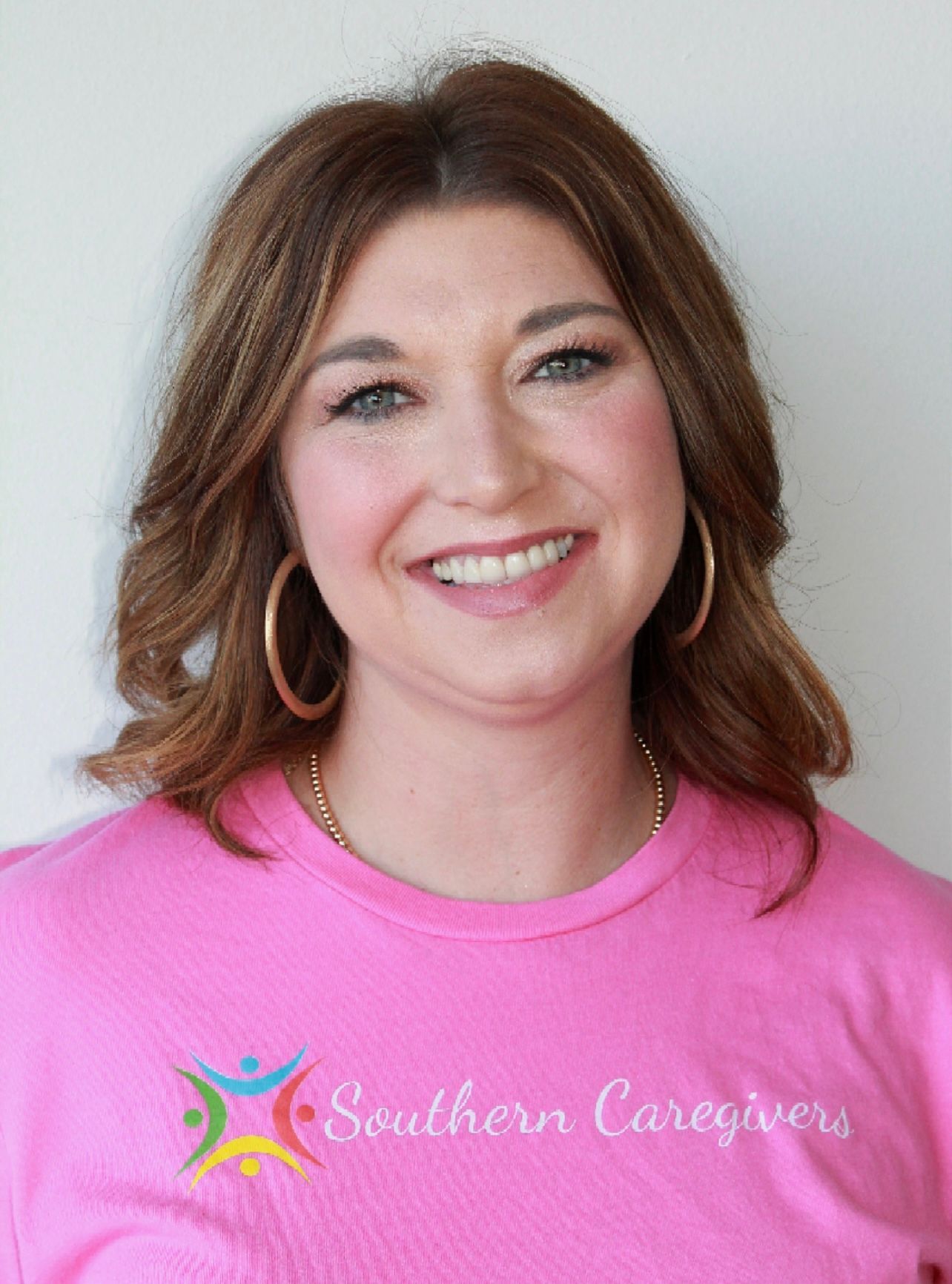 Smiling woman in a pink shirt with hoop earrings against a light background