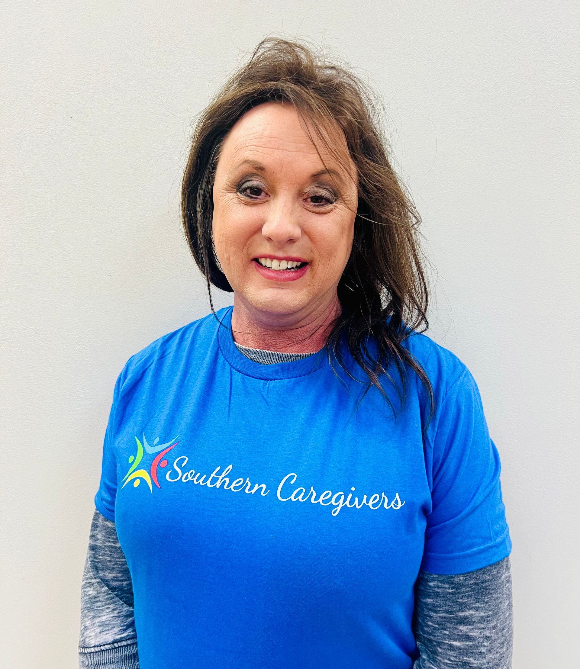 Smiling person in a black Southern Caregivers T-shirt standing against a plain light wall