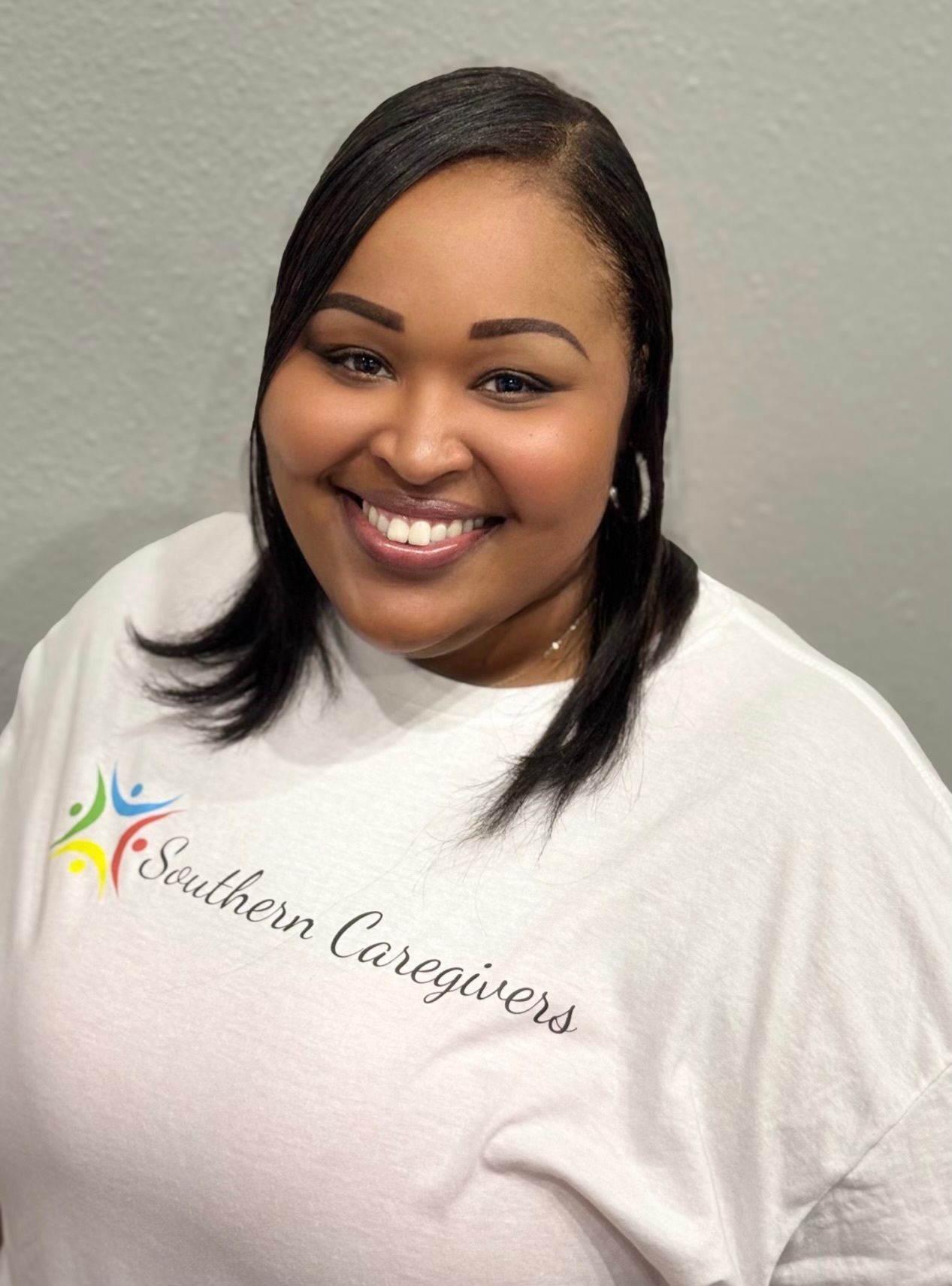 Smiling woman in a pink shirt with hoop earrings against a light background