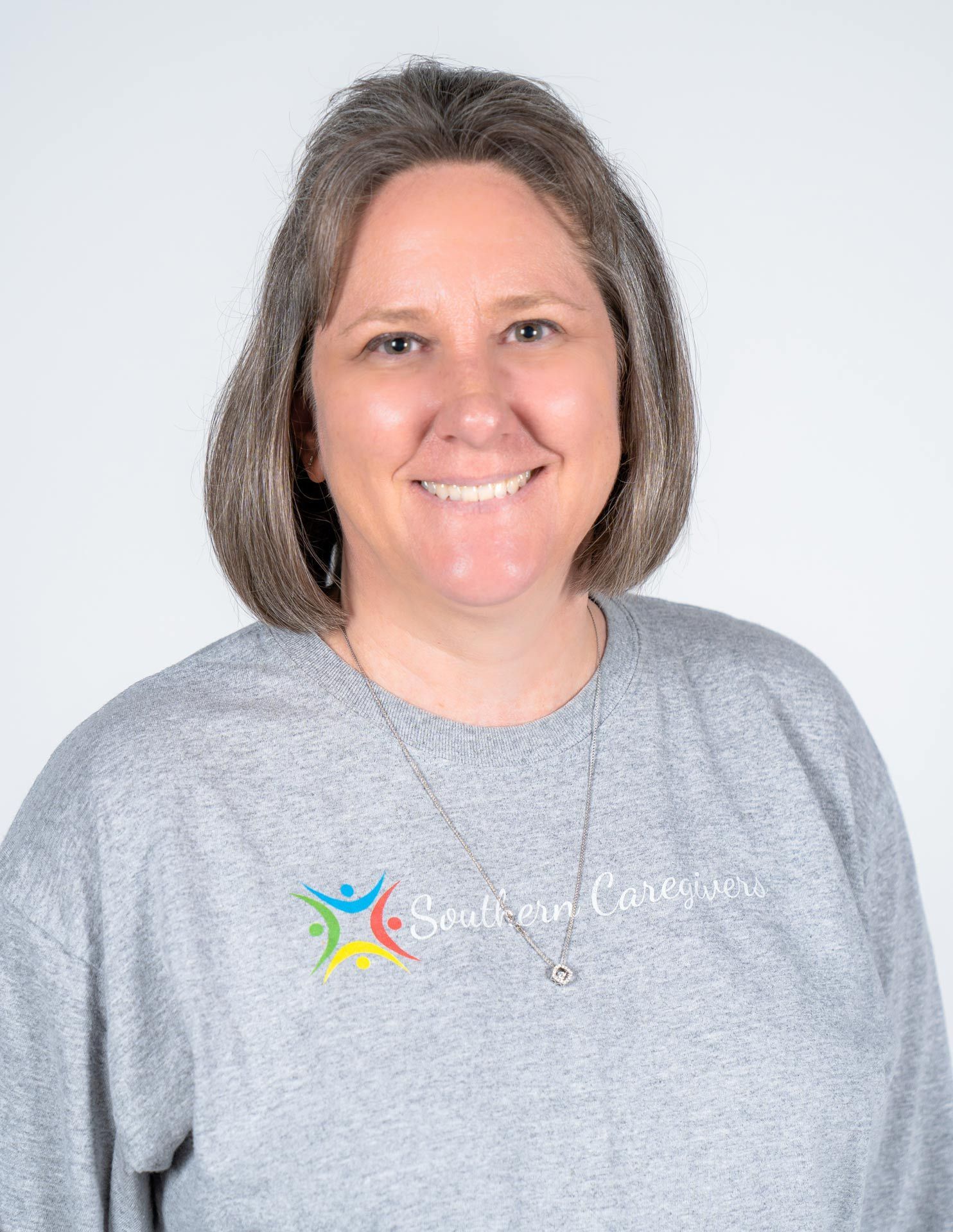 Smiling person in a gray sweatshirt against a light gray background