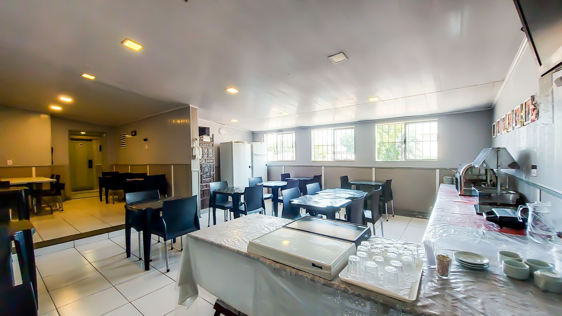 Um restaurante com mesas e cadeiras e uma mesa de bufê.