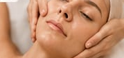 Primo piano di una donna che riceve un massaggio al viso, con gli occhi chiusi e rilassati.