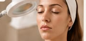 Una donna con gli occhi chiusi mentre uno strumento cosmetico le sfiora il viso in un ambiente spa.