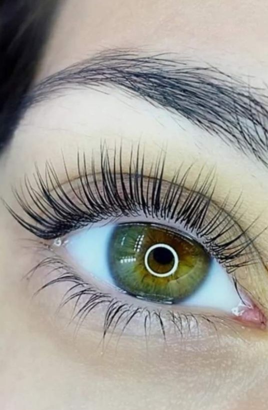 Primo piano del volto di una persona, con gli occhi rivolti verso l'alto, trucco naturale e illuminazione soffusa.