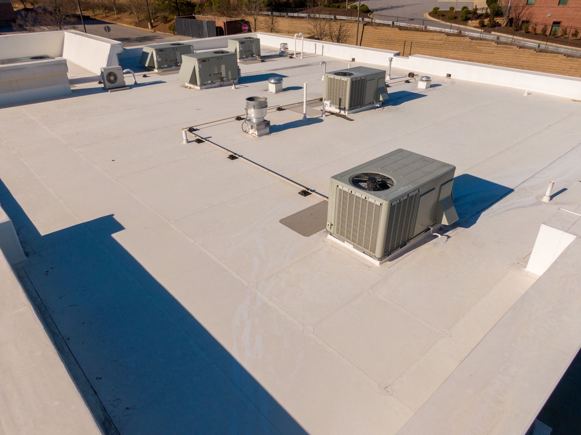 Rooftop condenser units on a white flat commercial roof