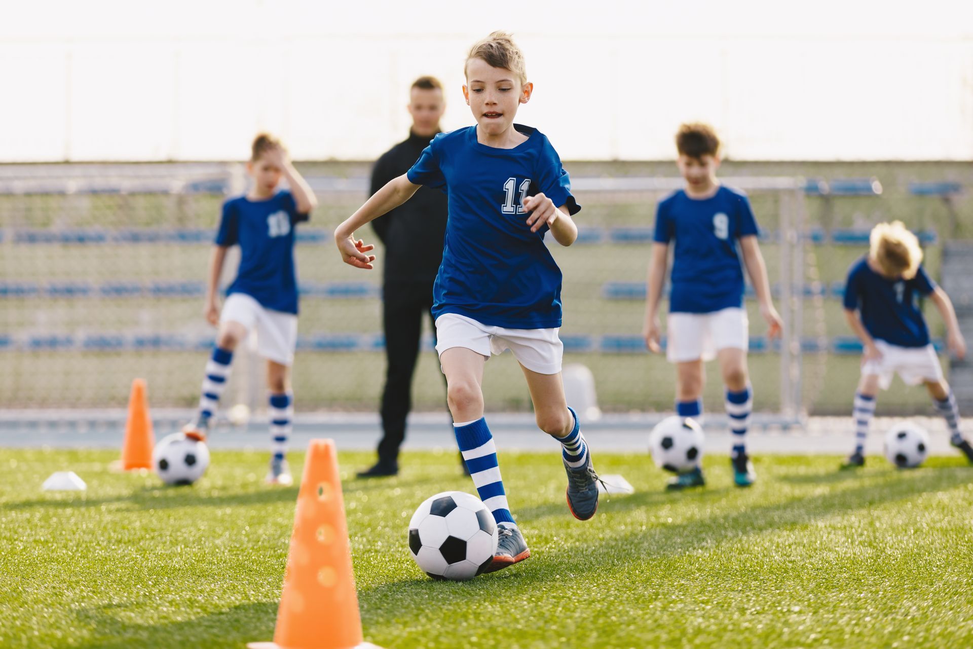 Youth soccer team practicing dribbling around cones.