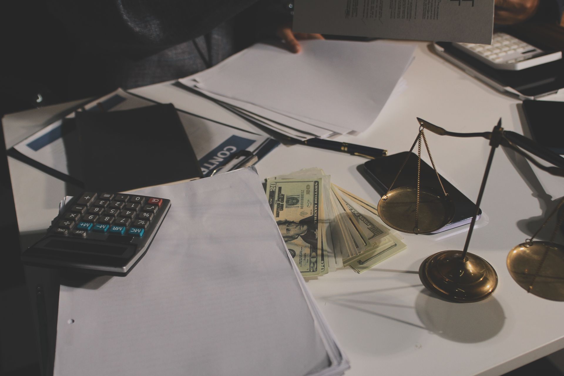 Desk with money, scales of justice, papers, and calculators.