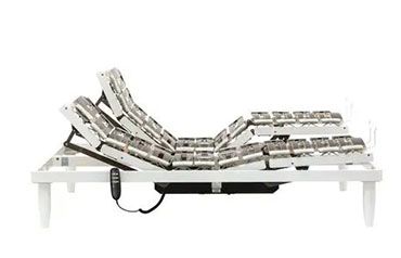 Una struttura letto regolabile di colore bianco, parzialmente sollevata, con telecomando portatile collegato tramite un cavo.