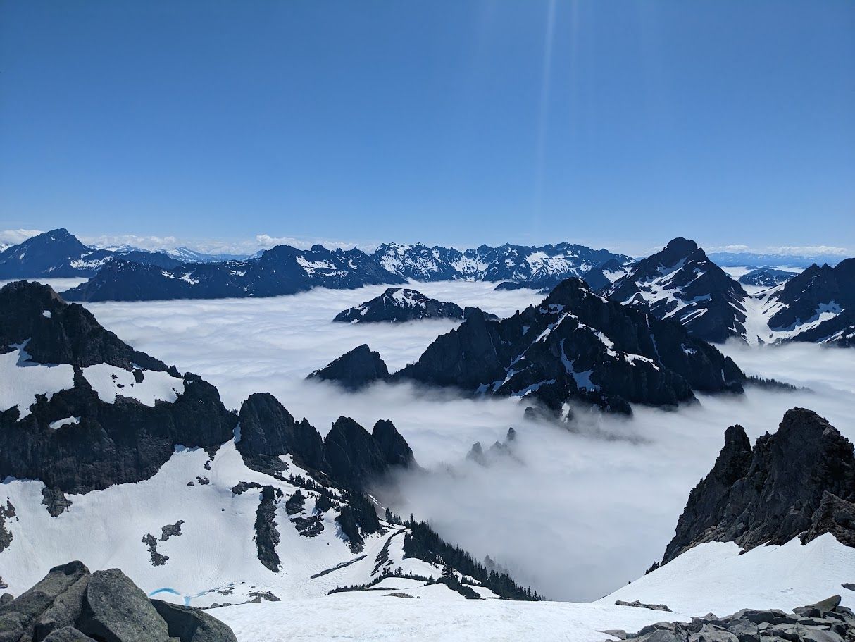 Snowy mountain peaks rising above low clouds under a clear blue sky Snowy mountain peaks rising above low clouds under a clear blue sky