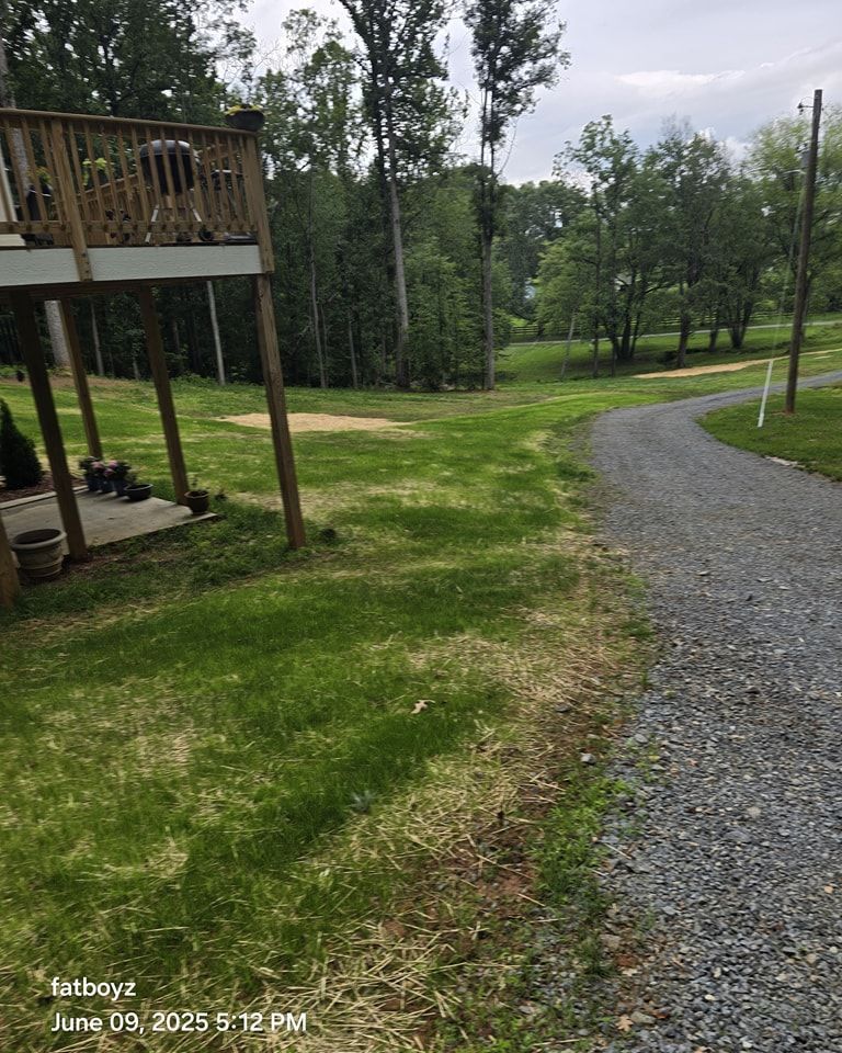 Curved gravel path through a grassy park with trees and a wooden deck on the left.