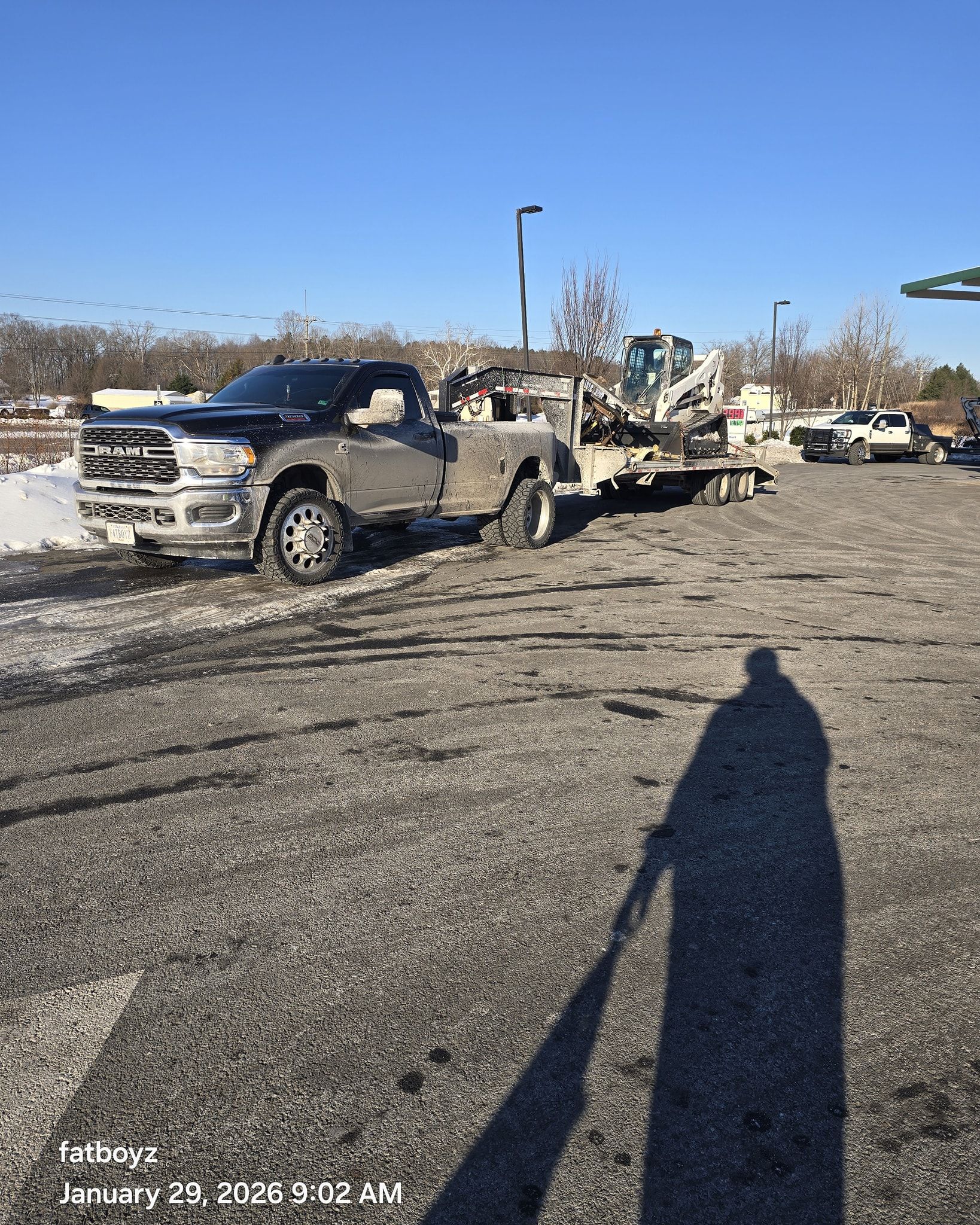 Damaged pickup truck in a snowy parking lot, with debris and another vehicle in the background.
