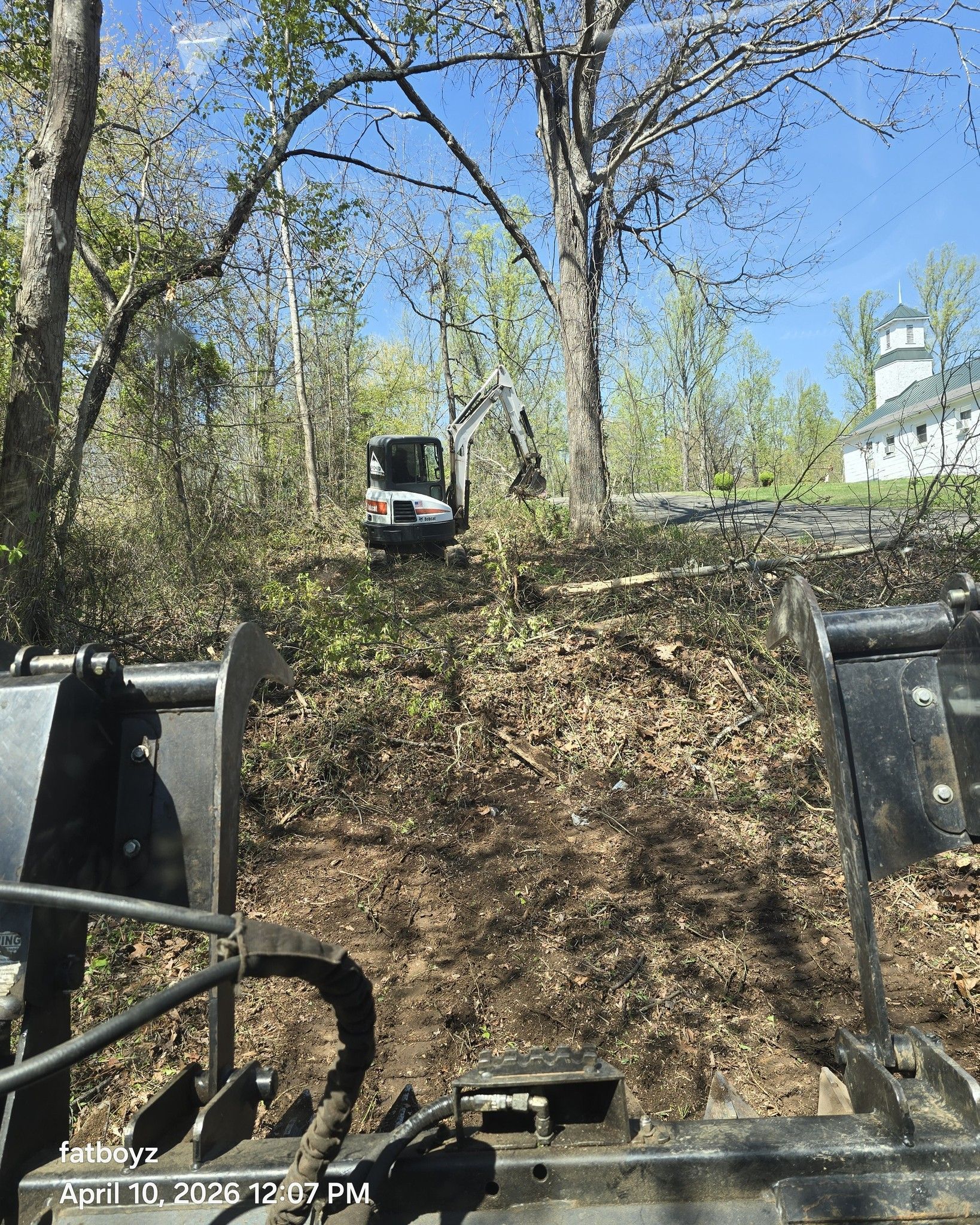 Riding a utility vehicle up a dirt hill with trees and a clear blue sky overhead