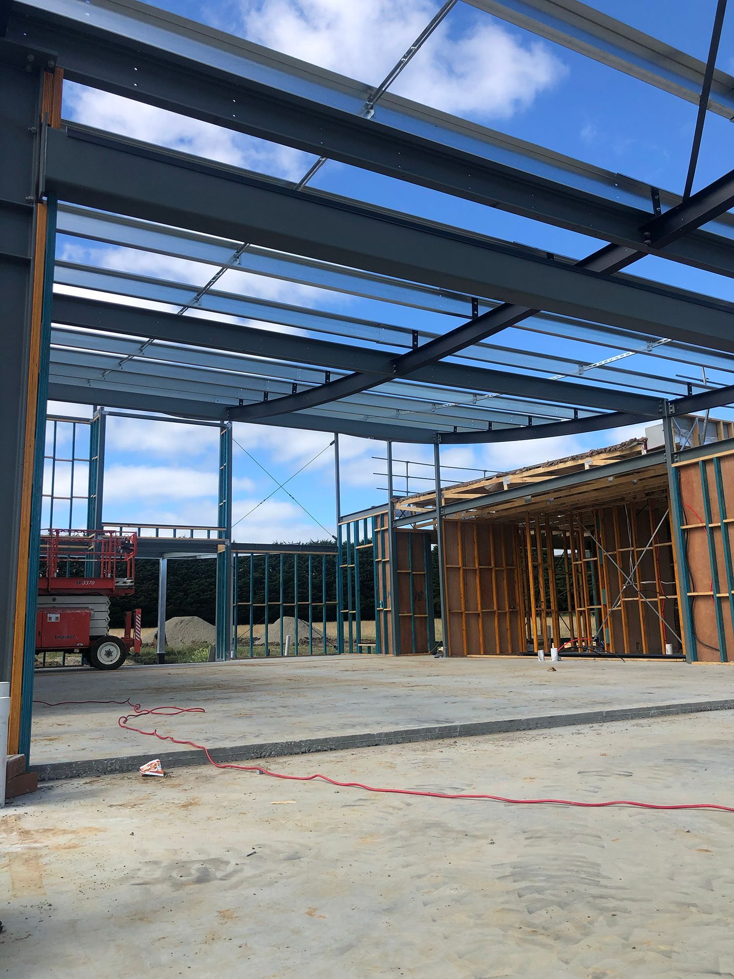 A large metal structure is being built in a parking lot.