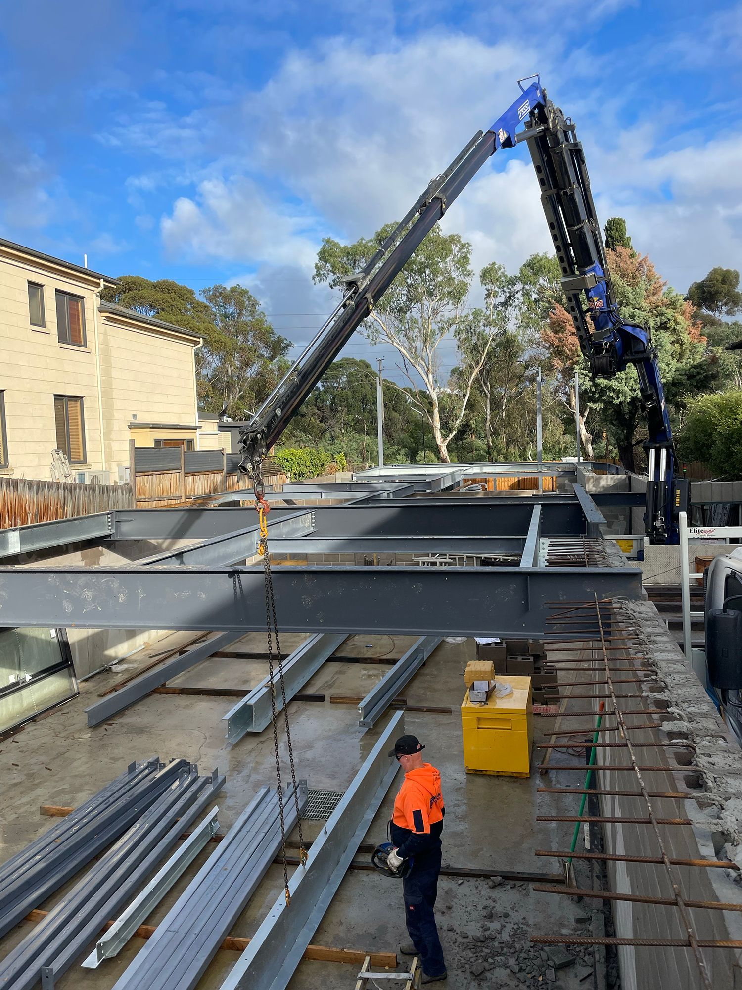 A man is standing next to a crane on a construction site.