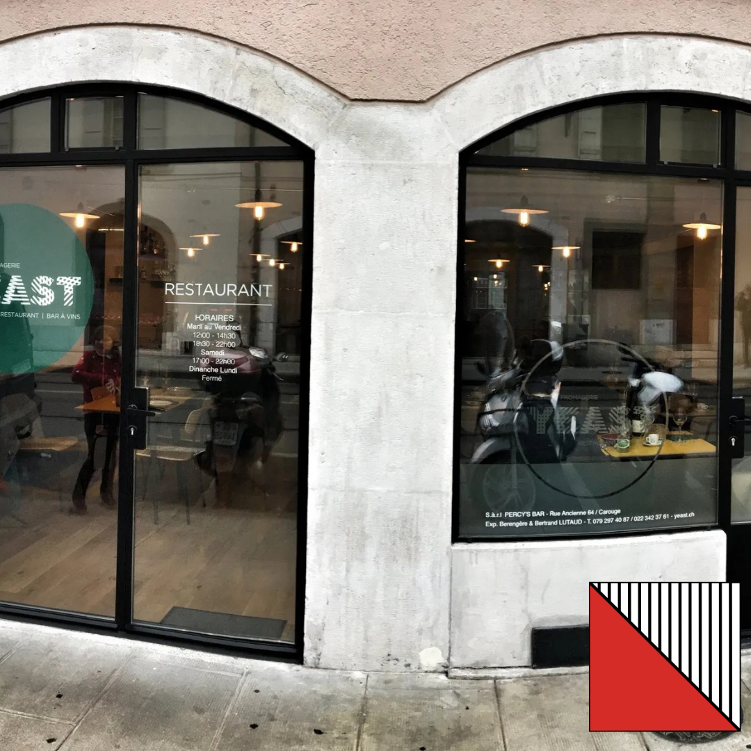 Façade vitrée avec fenêtres cintrées et enseigne de restaurant à côté d'une vitrine à vélos