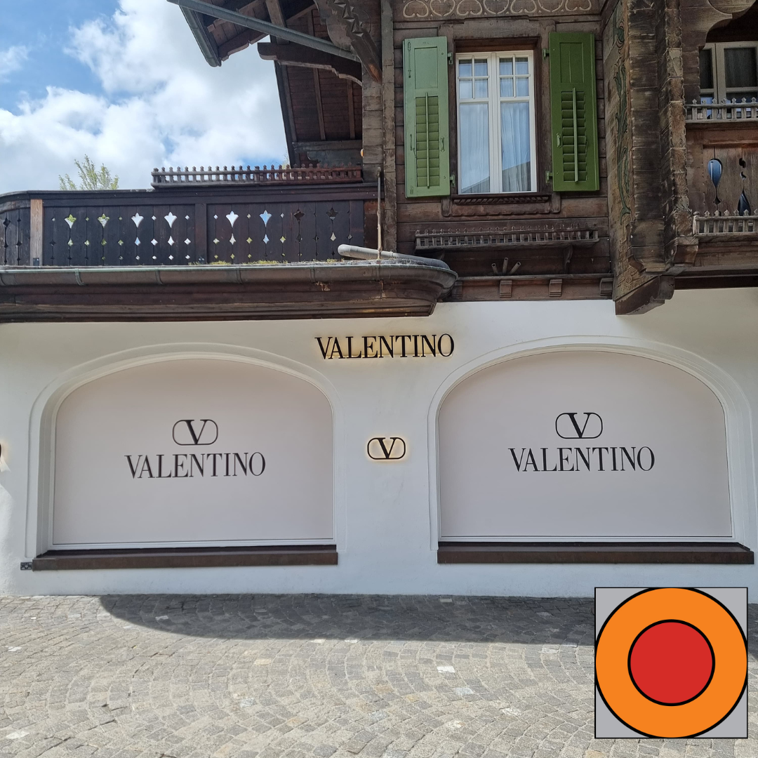 Façade de la boutique Valentino avec façade blanche et deux vitrines cintrées sous un balcon rustique en bois
