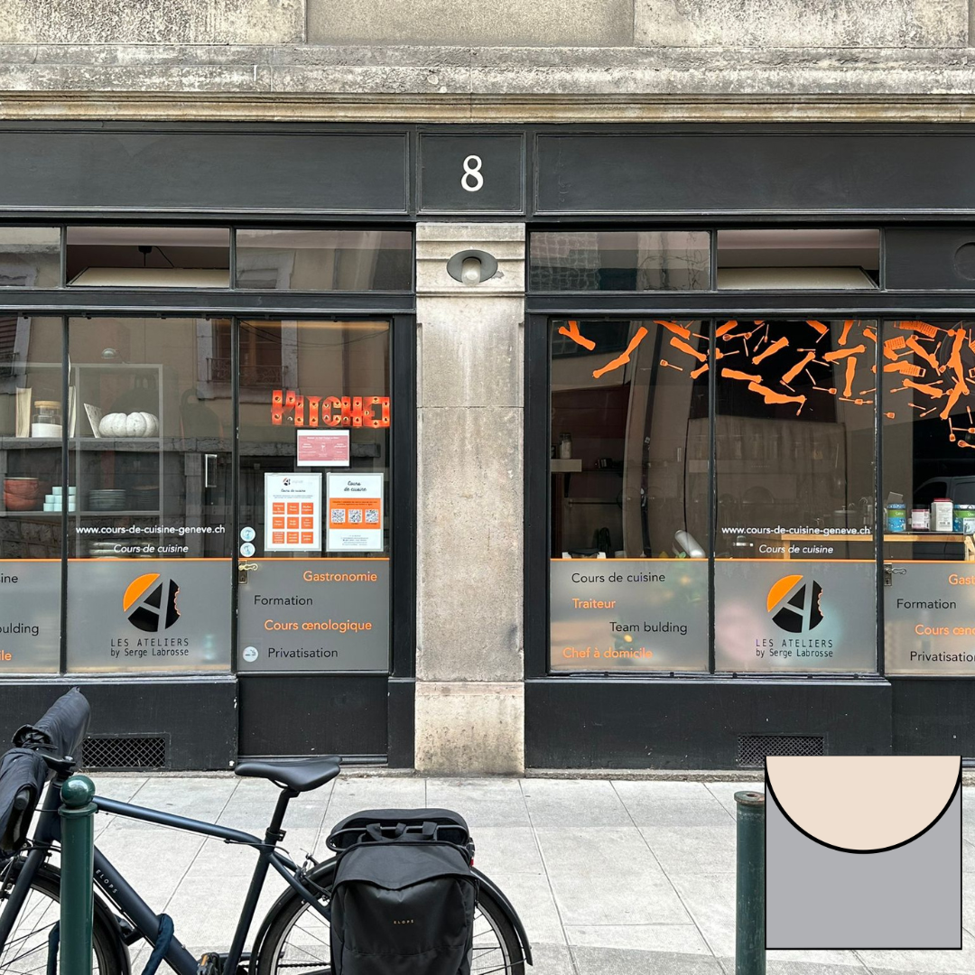 Façade de magasin avec de grandes vitrines et une enseigne orange ; un vélo est garé devant, sur le trottoir.