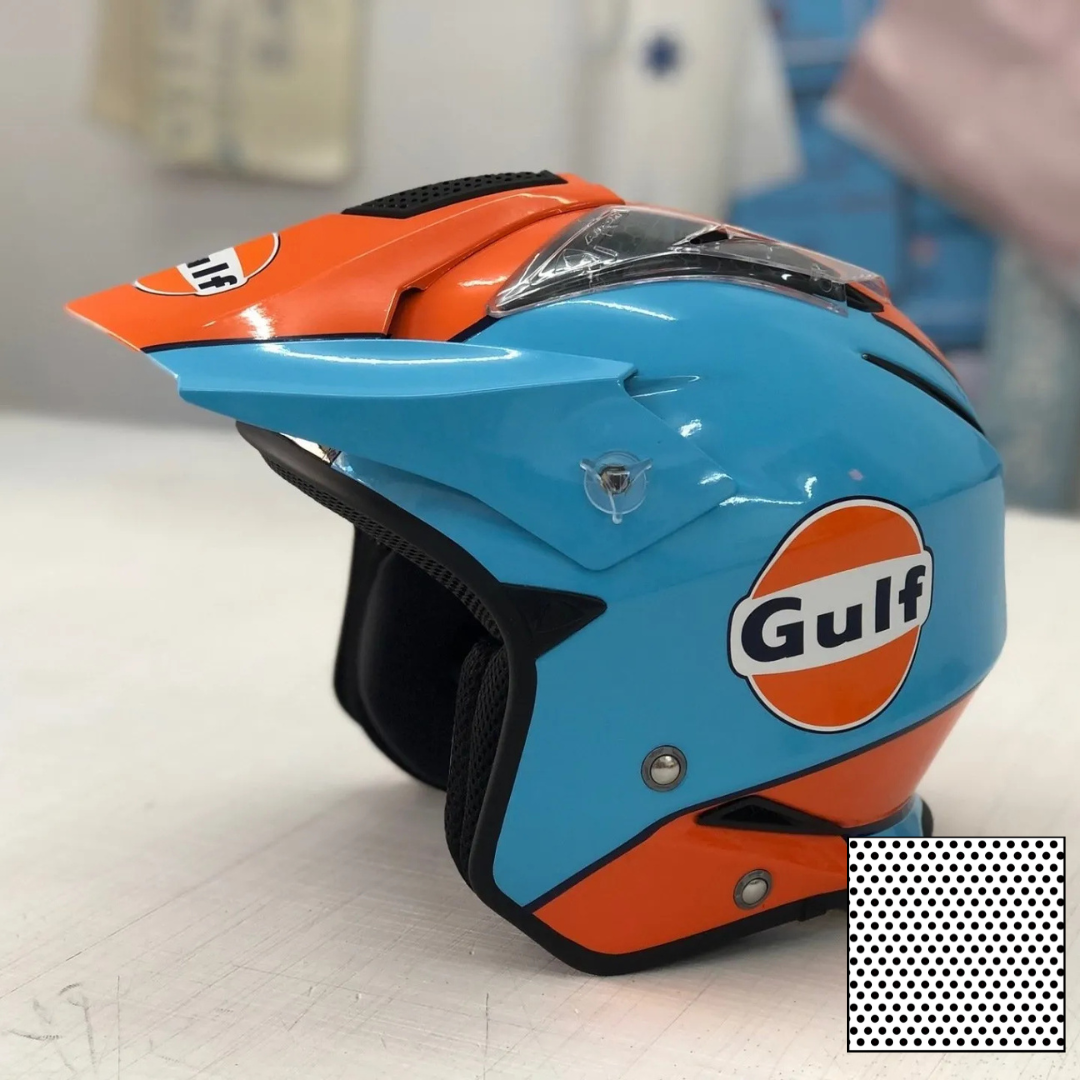 Casque de course Gulf bleu et orange posé sur une table, intérieur noir et arrière-plan flou.