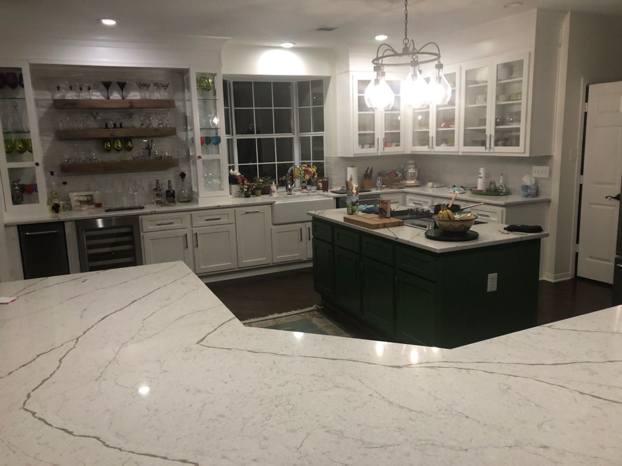 Kitchen with white cabinets, dark green island, and white countertops.