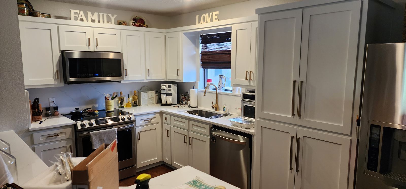 White kitchen with cabinets, stainless steel appliances, and a window. 