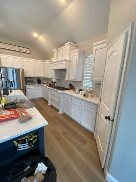 White kitchen with light wood floors, a blue island, and white cabinets.