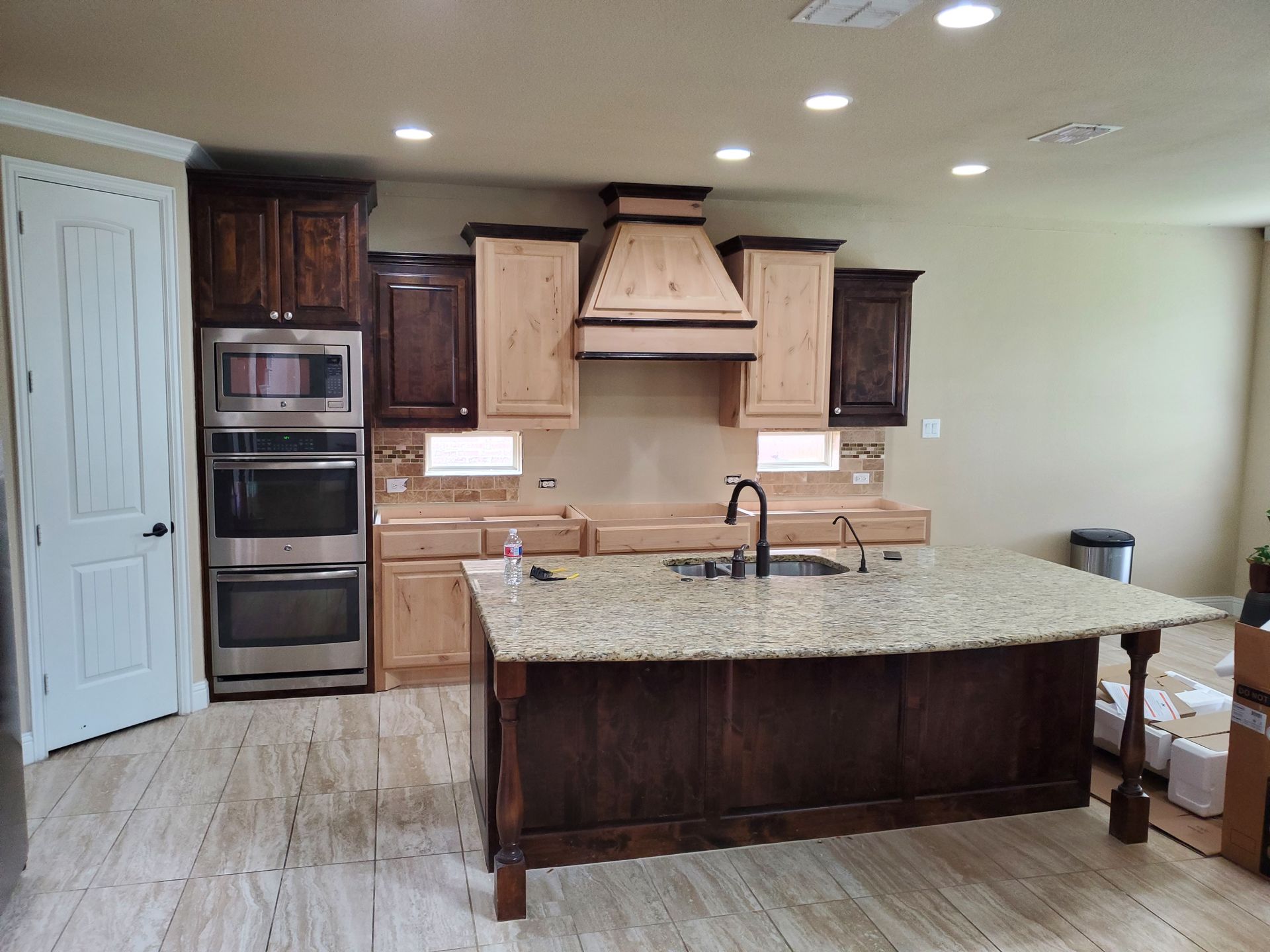Kitchen with brown and tan cabinets, granite countertops, and an island.