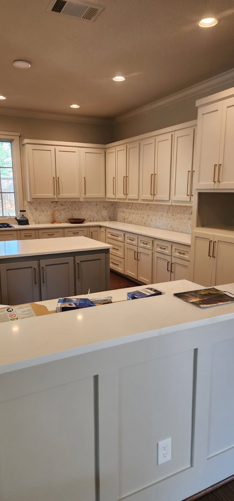 Kitchen with white cabinets, light countertops, and a gray island.