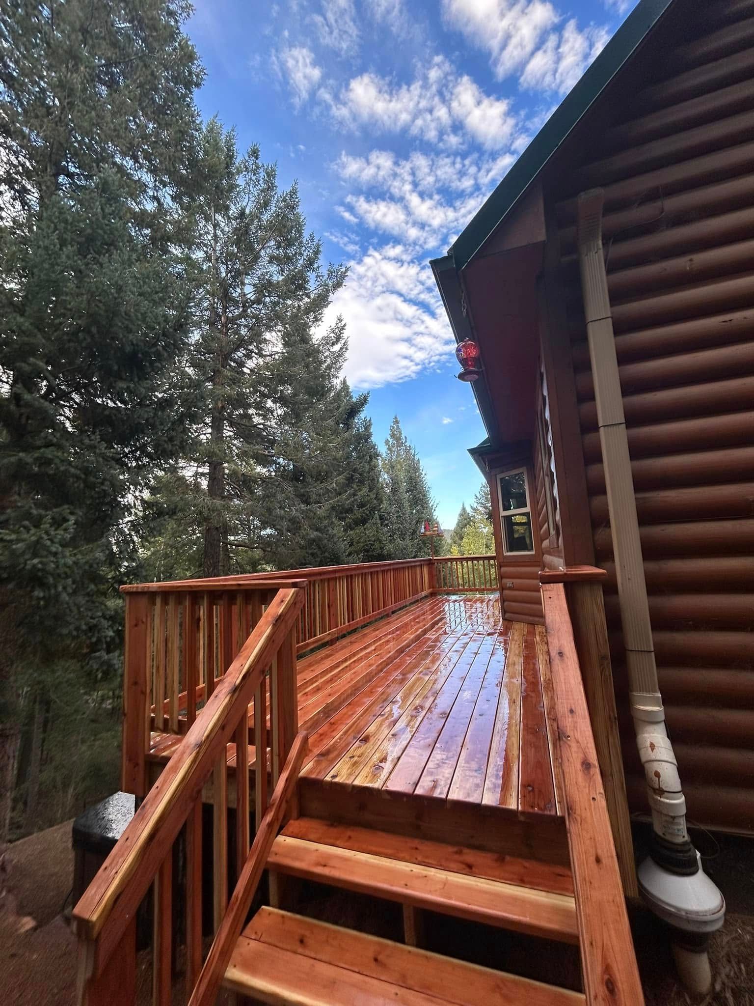 A wooden deck with stairs leading up to it next to a log cabin.