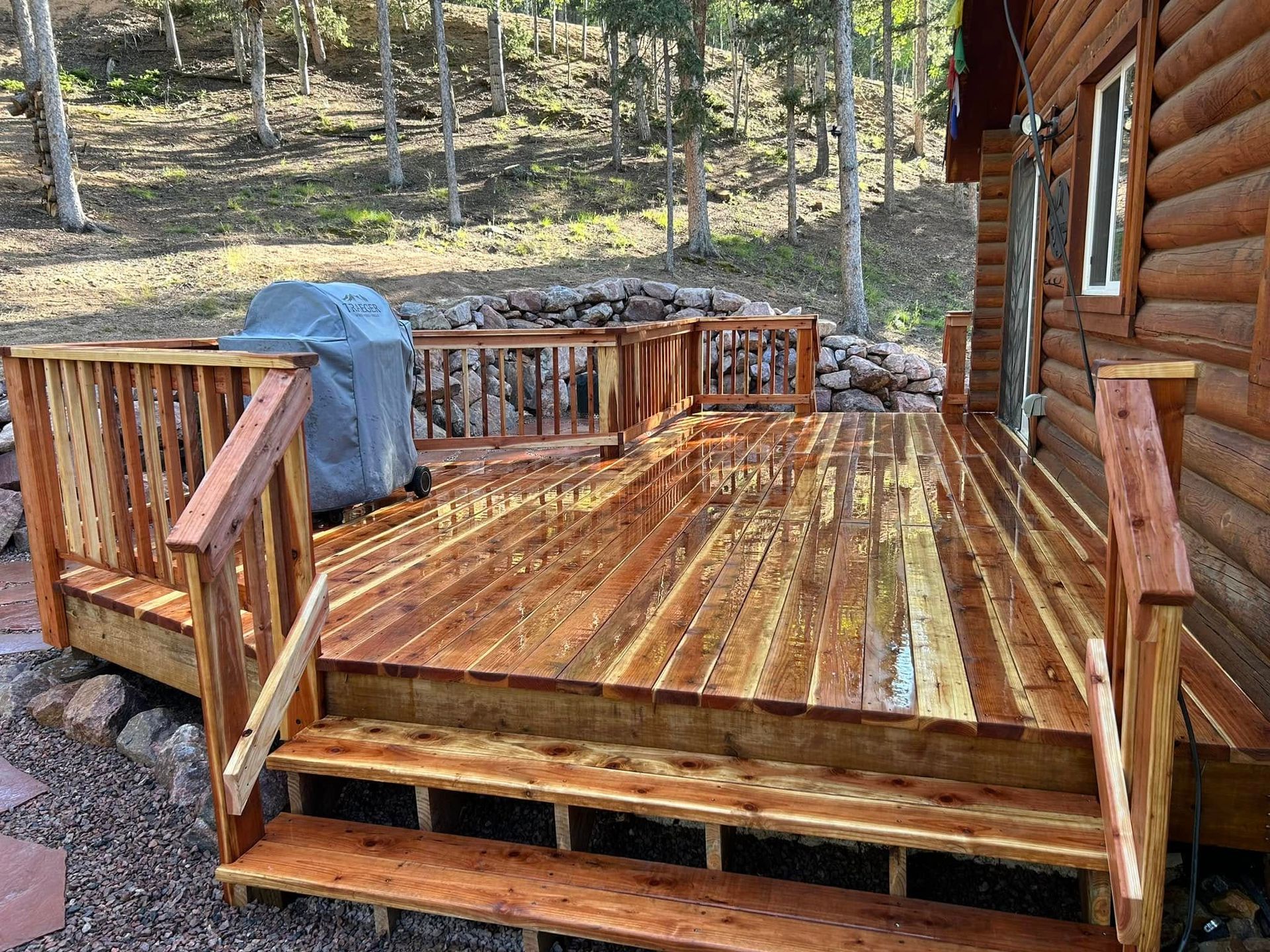 A wooden deck with stairs is in front of a log cabin.