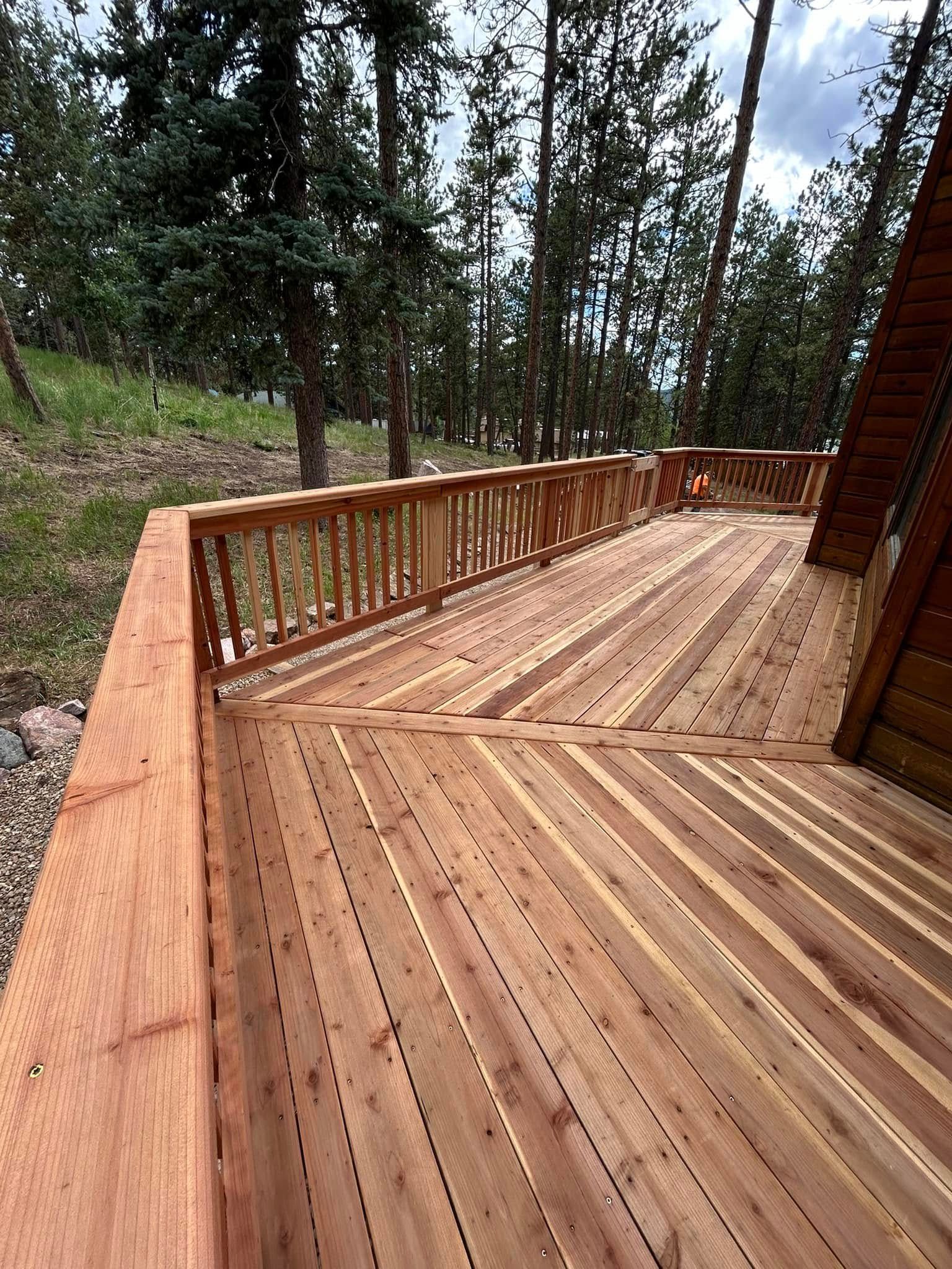 A wooden deck with stairs leading up to it in the woods.