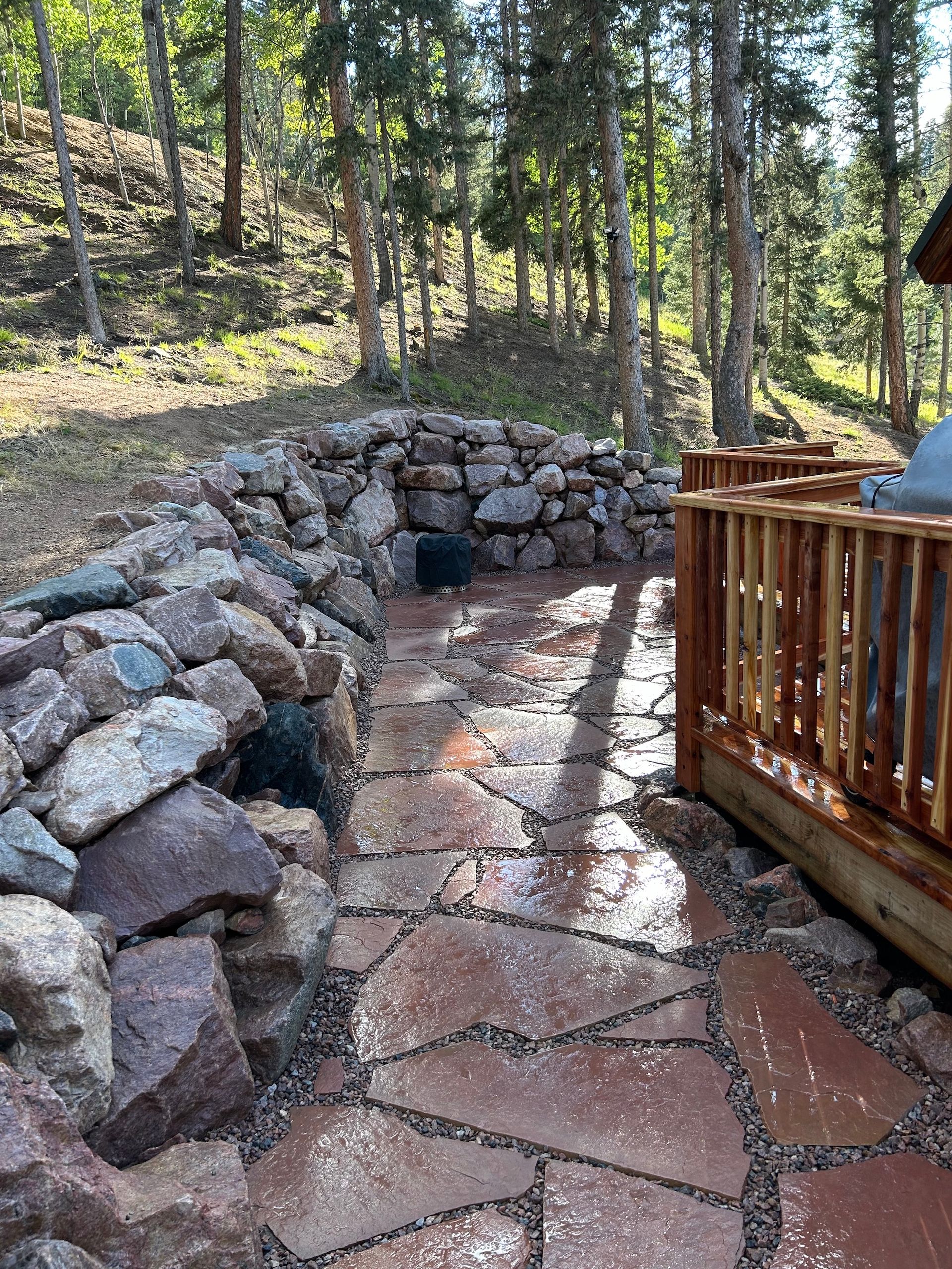 A stone walkway leading to a wooden deck in the woods.