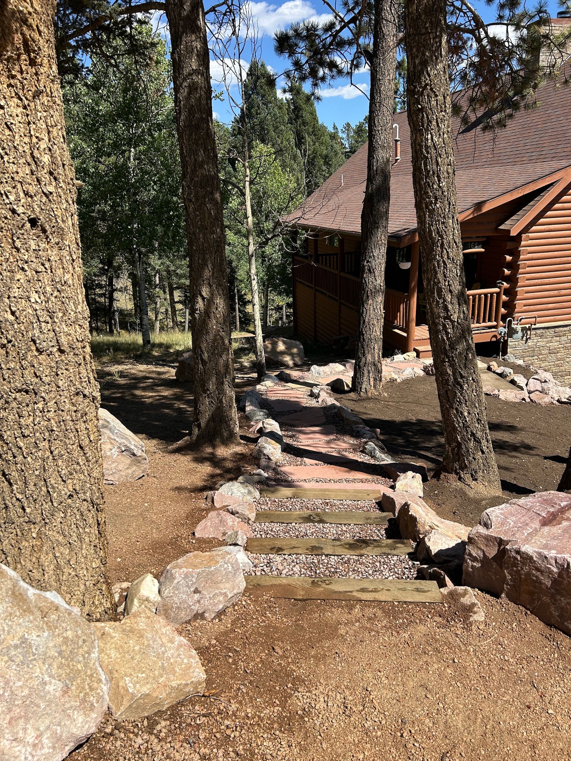 A log cabin in the woods with stairs leading up to it.