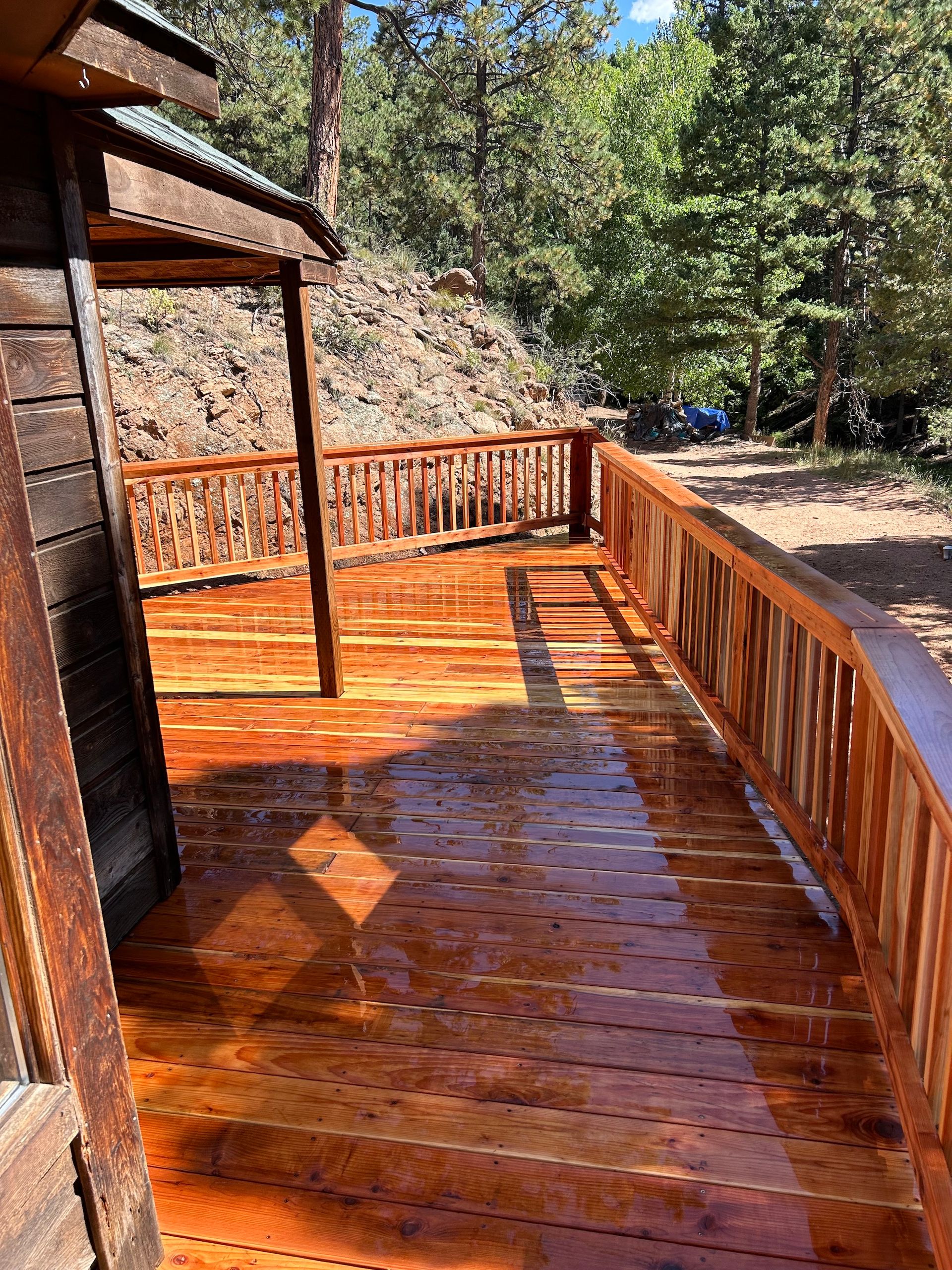 A wooden deck with a railing and trees in the background.