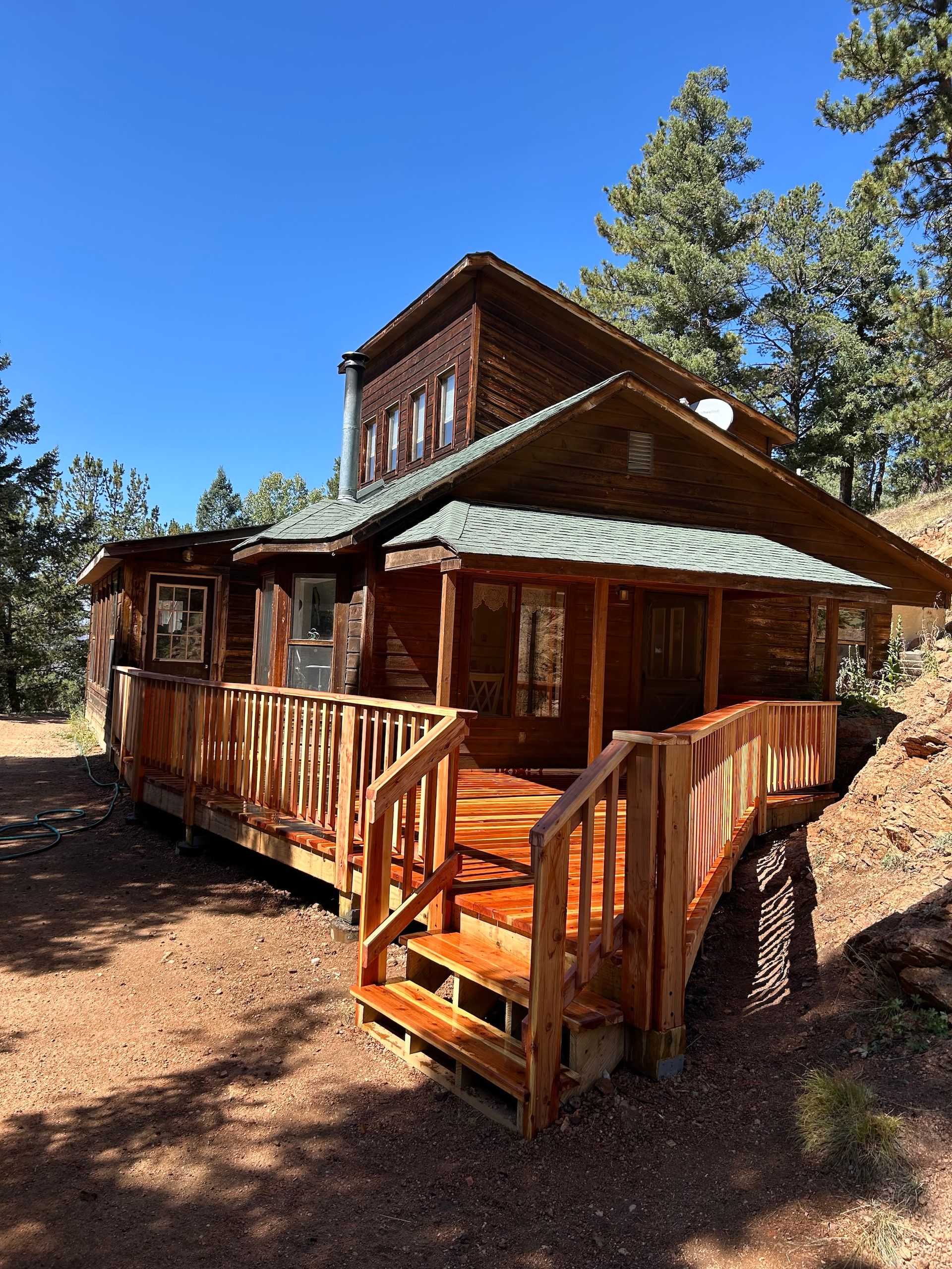 A large wooden house with a large deck and stairs leading up to it.