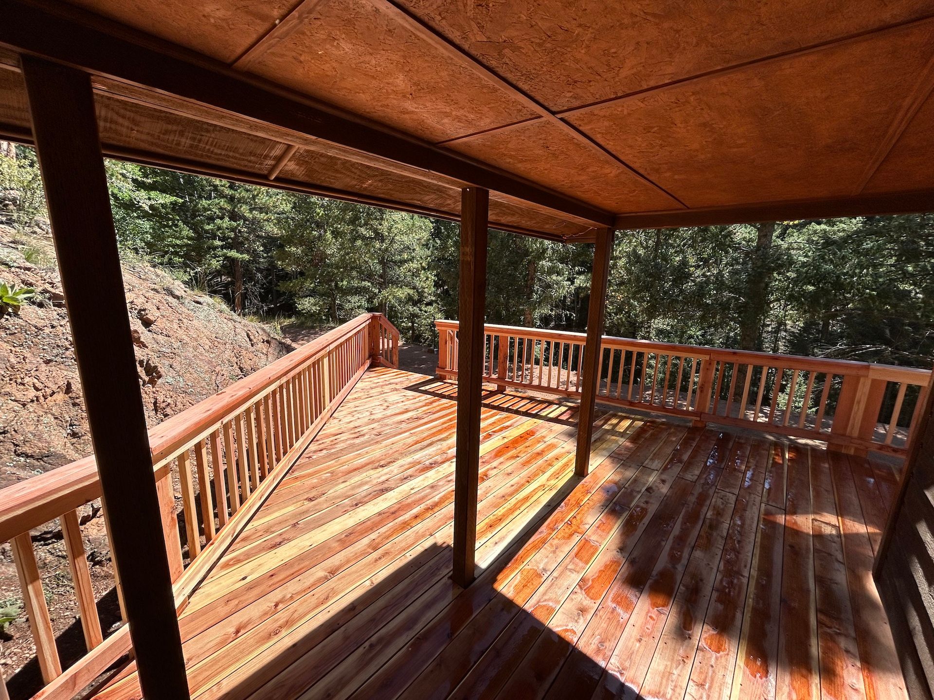 A wooden deck with a railing and trees in the background