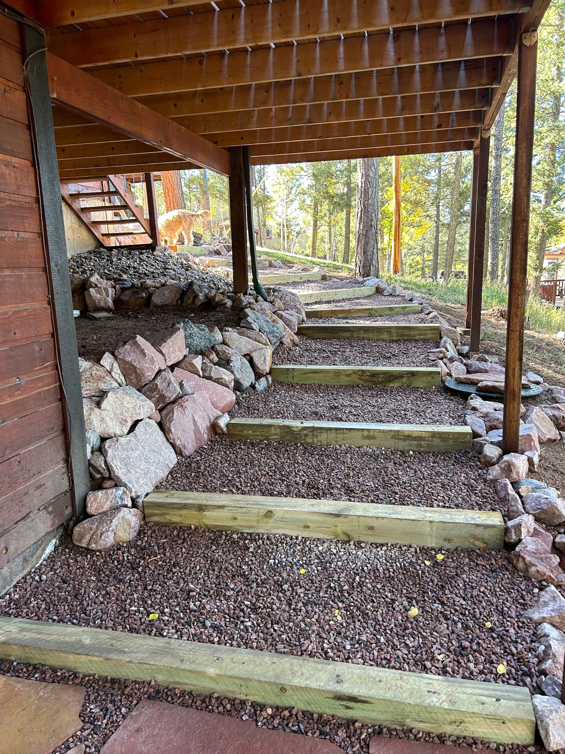 A wooden deck with stairs leading up to it in the woods.