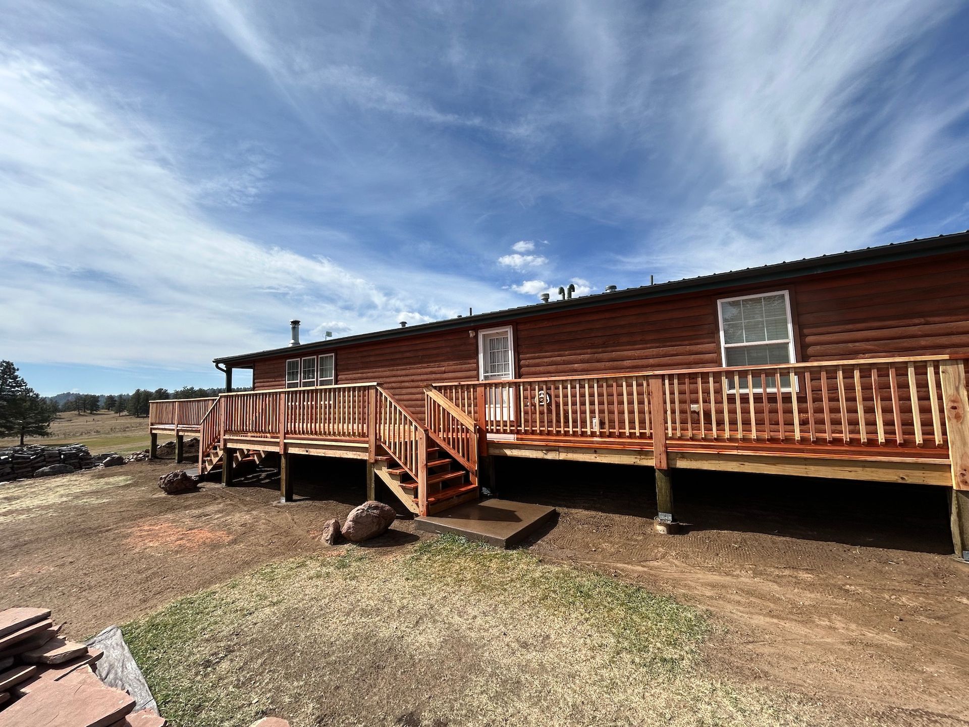 A log cabin with a large wooden deck and stairs.