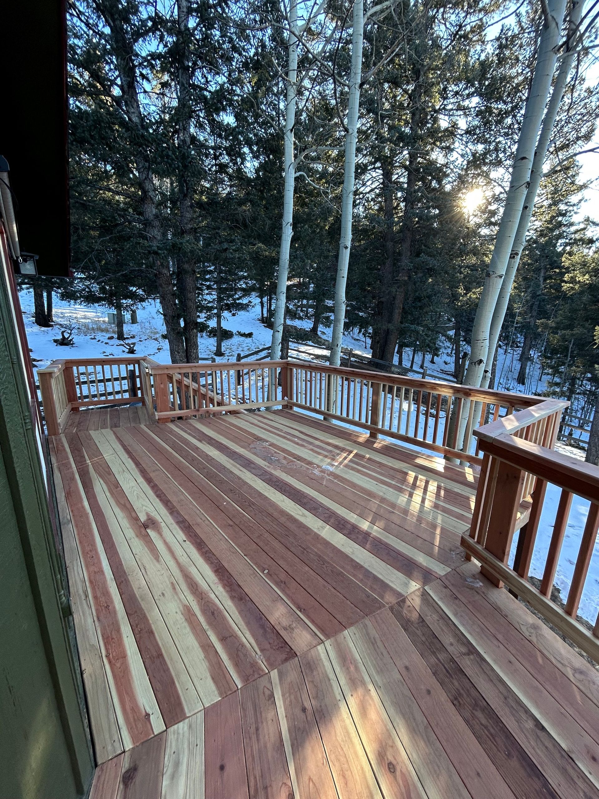 A wooden deck with stairs leading up to it and trees in the background.
