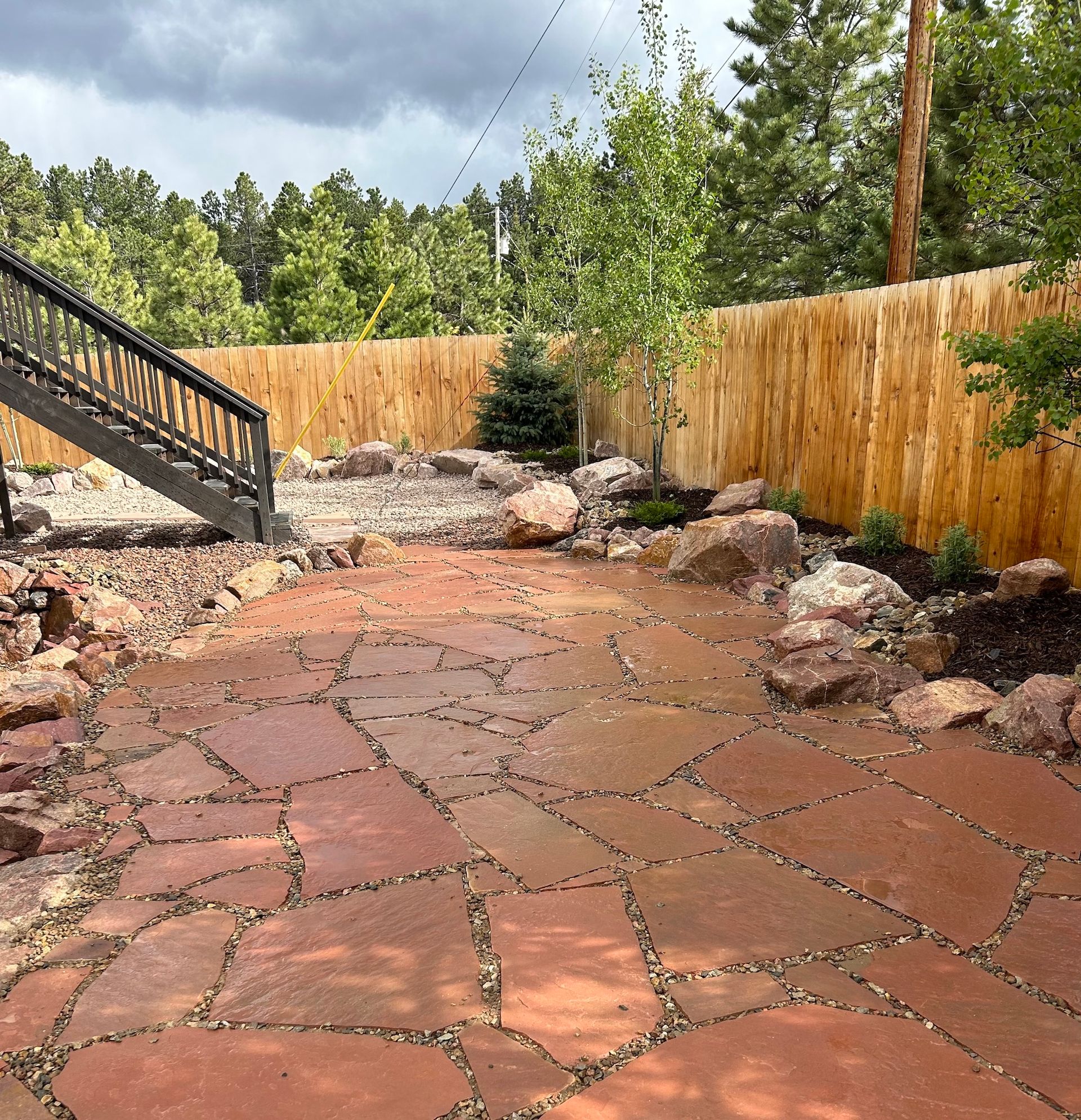 A stone patio with a wooden fence behind it